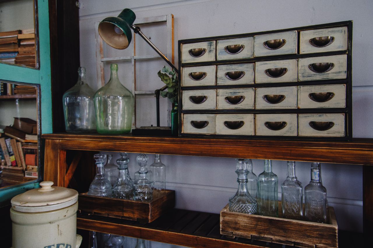 creative-02 A rustic indoor scene featuring a vintage cabinet and glass bottles on a wooden shelf.